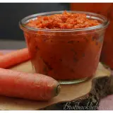 Ein Glas mit leckerer Karotten Marmelade, daneben frische Karotten.