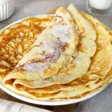 Ein Stapel goldbrauner Pfannkuchen, bestreut mit Zucker. Ein einfaches Pfannkuchen Rezept für jeden Tag.