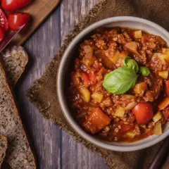 Herzhafter Bauerntopf mit Kartoffeln, Hackfleisch und Tomaten, garniert mit Basilikum. Dazu gibt es rustikales Brot. Ein tolles Rezept!