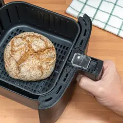 Ein goldbraunes Brot liegt im Korb eines Airfryers. Perfekt zum brot backen im airfryer für knusprigen Genuss.