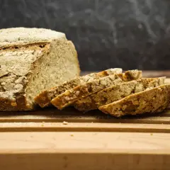 Frisch gebackenes Brot, angeschnitten auf einem Holzbrett. Die Kruste ist rustikal, die Scheiben zeigen die Porosität. Perfekt für die Frage: wie lange brotteig gehen lassen mit trockenhefe.