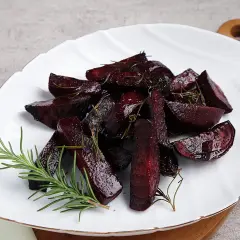 Gegarte rote Bete im Backofen, mit Rosmarin verfeinert, auf einem weißen Teller angerichtet.