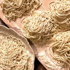 Frisch gemachte, glutenfreie Nudeln liegen auf einer Platte und einem Holzbrett. Perfekt für alle, die glutenfreie Nudeln selber machen wollen.