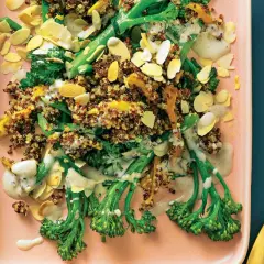 Bunter Quinoa-Salat mit wildem Brokkoli, Mandelsplittern und cremiger Sauce auf einem rosa Teller.
