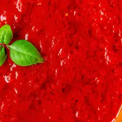 Frische Tomatensauce, die zeigt, wie einfach es ist, Tomatensauce selber zu machen. Ein Basilikumblatt liegt auf der leuchtend roten Masse.