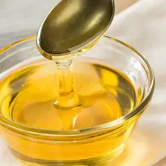 Goldener Sirup fließt von einem Löffel in eine Glasschale. Eine süße Alternative, wenn Sie Agavendicksaft ersetzen möchten.