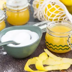 Zutaten für gelierzucker selber machen: Zucker in einer Schüssel, Apfelscheiben, Äpfel und Zitronenschalen.