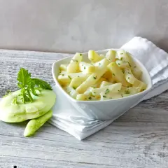 Kohlrabi kochen: Ein cremiges Gericht mit Kohlrabi-Stücken und frischer Petersilie, daneben ein roher Kohlrabi.