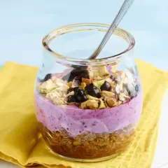 Ein Glas mit Joghurt, Beeren und Nüssen. Sojaflocken wie essen? Dieses leckere Frühstück ist eine tolle Option!