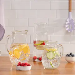 Erfrischendes infused wasser mit Zitrone, Gurke und Beeren in Glaskaraffen und einem Glas.