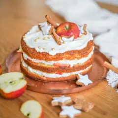 Ein Apfelkuchen, der mit Sahne, Zimtstangen, Sternen-Plätzchen und goldenen Perlen verziert ist. So lässt sich eine Backmischung aufpeppen!