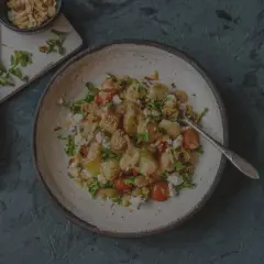 Herzhafter Salat mit bratkartoffeln aus rohen kartoffeln, Feta, Kirschtomaten und Rucola, garniert mit Mandelsplittern.