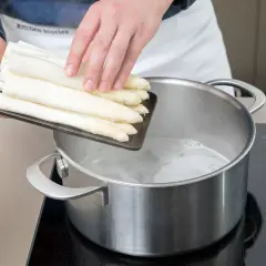 Frische weiße Spargelstangen werden in kochendes Wasser gegeben. Ob mit oder ohne Deckel, das Spargel kochen beginnt jetzt.