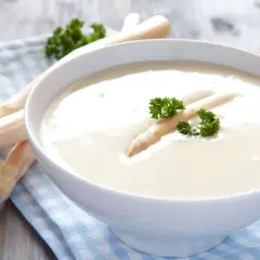 Cremige Spargelsuppe aus Spargelschalen, garniert mit einem Spargelspitz und Petersilie.