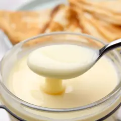 Cremige, selbstgemachte gezuckerte Kondensmilch in einem Glas, bereit zum Verfeinern von Desserts.