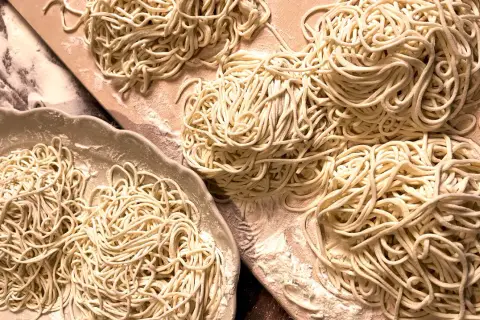 Frisch gemachte, glutenfreie Nudeln liegen auf einer Platte und einem Holzbrett. Perfekt für alle, die glutenfreie Nudeln selber machen wollen.