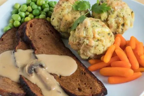 Herzhaftes Gericht mit Scheiben von seitan selber machen, dazu Klöße, Erbsen und Karotten.