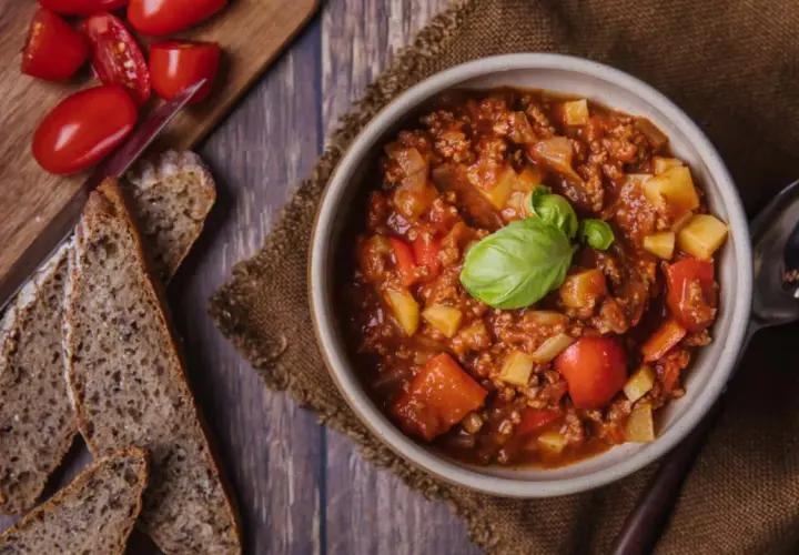 Herzhafter Bauerntopf mit Kartoffeln, Hackfleisch und Tomaten, garniert mit Basilikum. Dazu gibt es rustikales Brot. Ein tolles Rezept!
