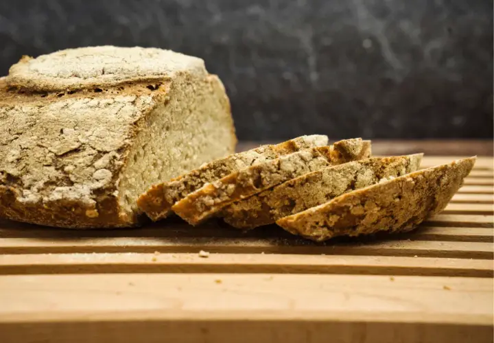 Frisch gebackenes Brot, angeschnitten auf einem Holzbrett. Die Kruste ist rustikal, die Scheiben zeigen die Porosität. Perfekt für die Frage: wie lange brotteig gehen lassen mit trockenhefe.