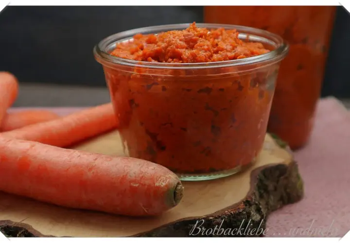 Ein Glas mit leckerer Karotten Marmelade, daneben frische Karotten.
