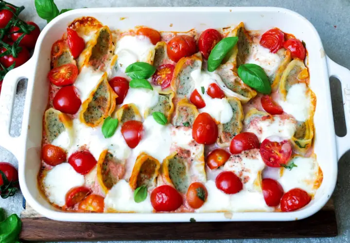 Herzhafter Maultaschen Auflauf mit Kirschtomaten und geschmolzenem Mozzarella, garniert mit frischem Basilikum.