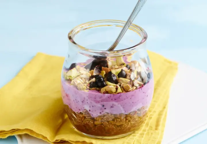 Ein Glas mit Joghurt, Beeren und Nüssen. Sojaflocken wie essen? Dieses leckere Frühstück ist eine tolle Option!