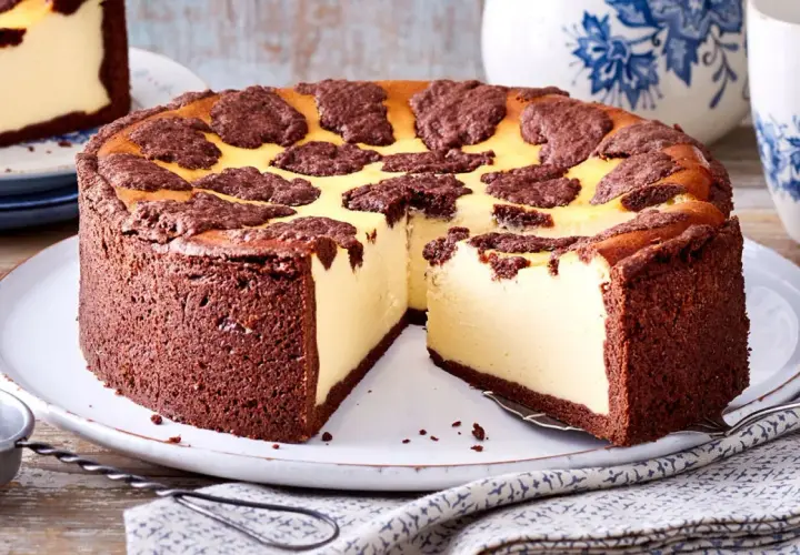 Ein saftiger russischer Zupfkuchen mit Schokoladenboden und cremiger Käsemasse, dekoriert mit dunklen Schokoladenstückchen.