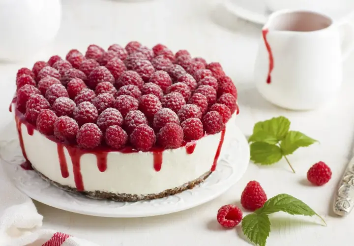 Ein köstlicher Kuchen ohne Backen, bedeckt mit frischen Himbeeren und Himbeersauce.