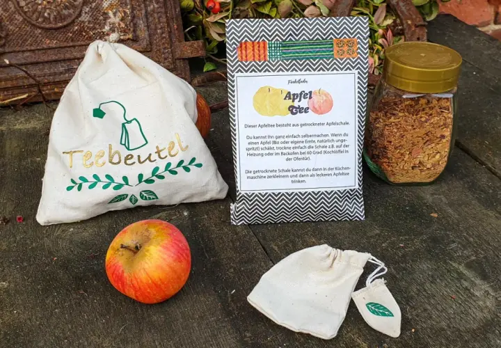 Zutaten für Apfeltee selber machen: Apfel, getrocknete Apfelschale im Glas, Teebeutel-Säckchen.