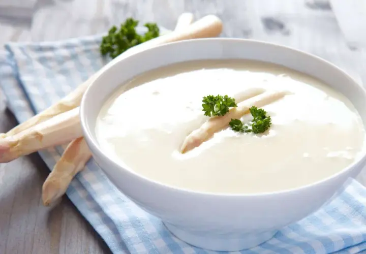 Cremige Spargelsuppe aus Spargelschalen, garniert mit einem Spargelspitz und Petersilie.