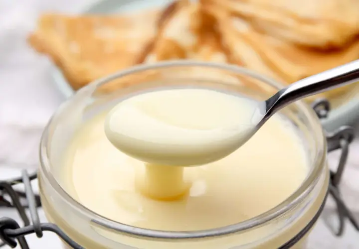 Cremige, selbstgemachte gezuckerte Kondensmilch in einem Glas, bereit zum Verfeinern von Desserts.