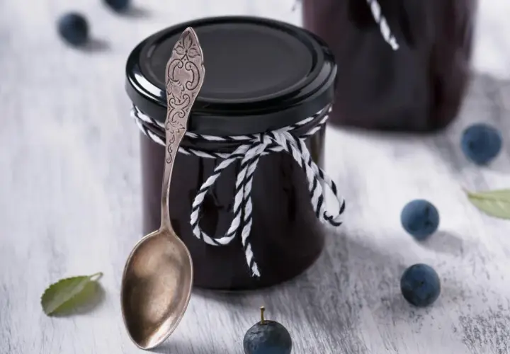 Glas mit Schlehenmarmelade, Löffel und Schlehen. Perfekt für Schlehen Rezepte.