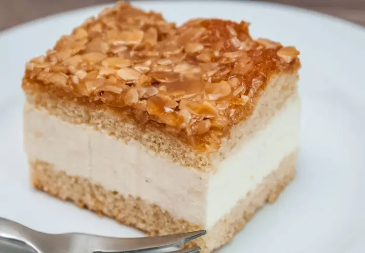Ein Stück Bienenstich-Kuchen mit cremiger Füllung und karamellisierten Mandeln. Ein leckeres Rezept für den süßen Genuss.