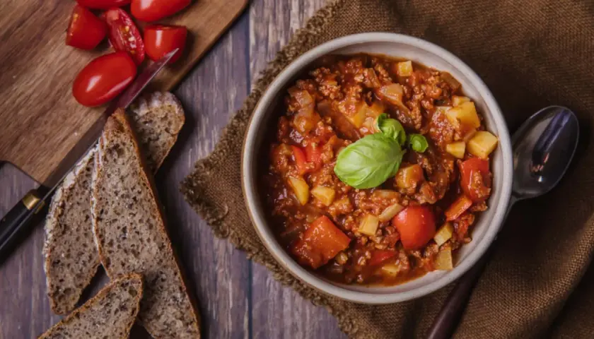 Herzhafter Bauerntopf mit Kartoffeln, Hackfleisch und Tomaten, garniert mit Basilikum. Dazu gibt es rustikales Brot. Ein tolles Rezept!
