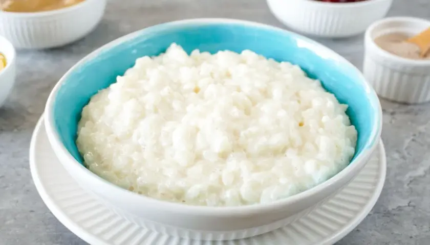 Cremiger Milchreis im blauen Schälchen, bereit für Zimt und Apfelmus. Ein einfaches Milchreis Rezept für gemütliche Momente.