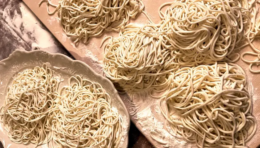 Frisch gemachte, glutenfreie Nudeln liegen auf einer Platte und einem Holzbrett. Perfekt für alle, die glutenfreie Nudeln selber machen wollen.