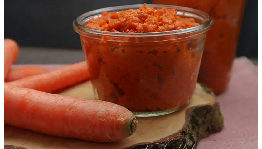 Ein Glas mit leckerer Karotten Marmelade, daneben frische Karotten.