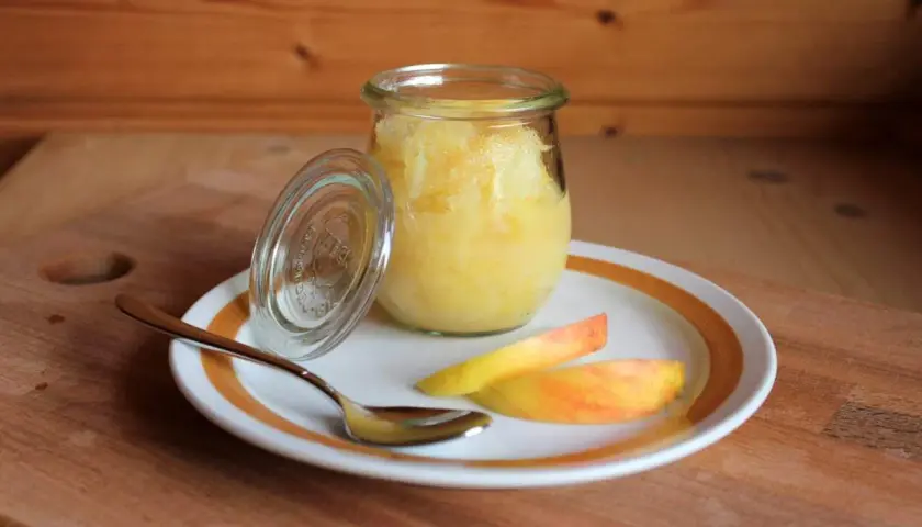 Glas mit selbstgemachtem Apfelmus, daneben Apfelspalten und ein Löffel. Perfekt zum Apfelmark selber machen!
