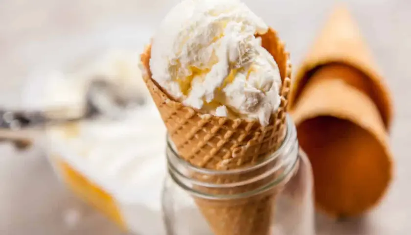 Cremiges griechischer joghurt eis ohne eismaschine im Waffelhörnchen, daneben leere Hörnchen.