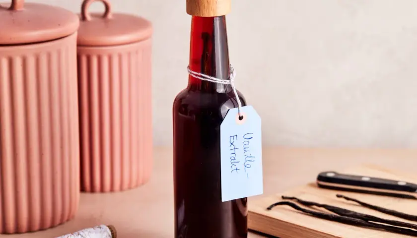 Flasche mit selbstgemachtem Vanilleextrakt, Vanilleschoten und Schnur.