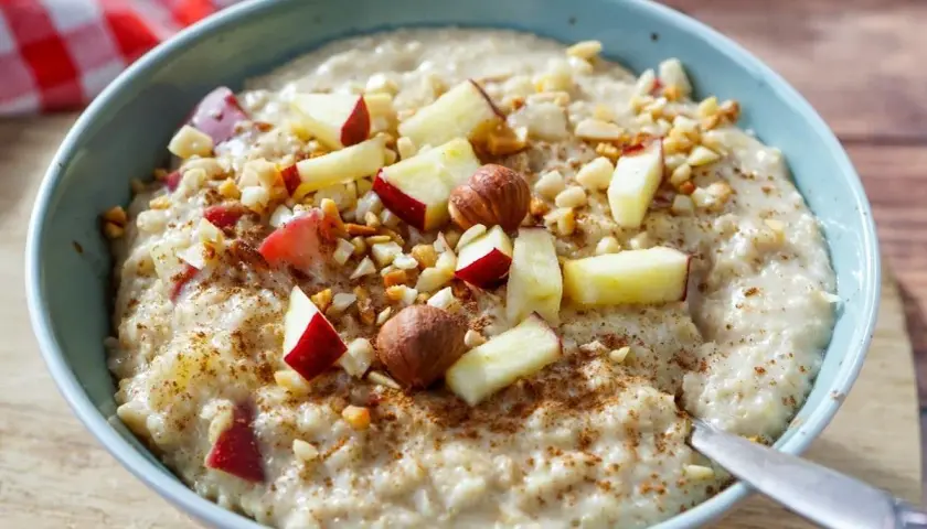 Schüssel mit cremigem Porridge, garniert mit Apfelstücken, Nüssen und Zimt. Perfekt, um Porridge kalt zu essen.