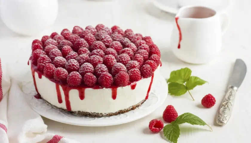 Ein köstlicher Kuchen ohne Backen, bedeckt mit frischen Himbeeren und Himbeersauce.