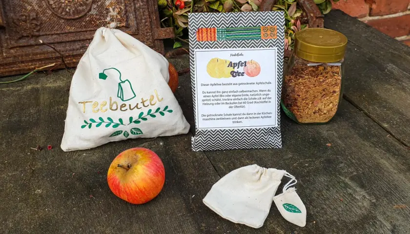 Zutaten für Apfeltee selber machen: Apfel, getrocknete Apfelschale im Glas, Teebeutel-Säckchen.