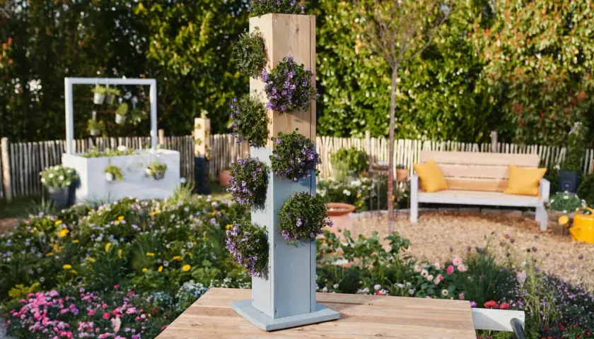 Ein vertikaler Pflanzturm mit lila Blüten, perfekt für alle, die einen Pflanzturm selber bauen möchten.