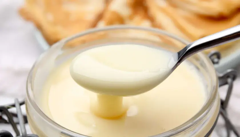 Cremige, selbstgemachte gezuckerte Kondensmilch in einem Glas, bereit zum Verfeinern von Desserts.