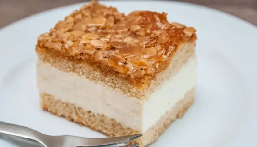 Ein Stück Bienenstich-Kuchen mit cremiger Füllung und karamellisierten Mandeln. Ein leckeres Rezept für den süßen Genuss.