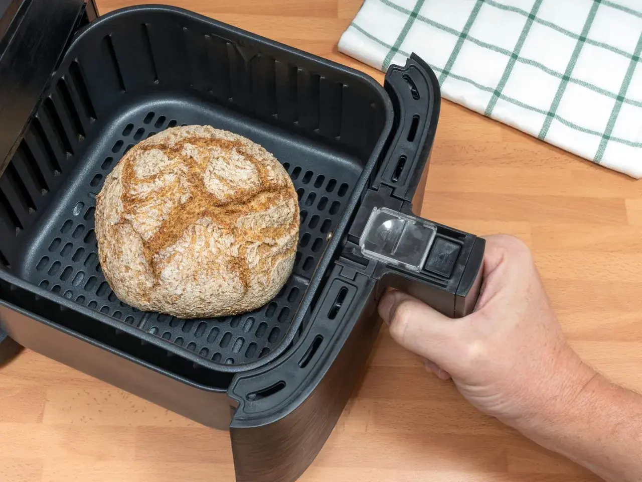 Ein goldbraunes Brot liegt im Korb eines Airfryers. Perfekt zum brot backen im airfryer für knusprigen Genuss.