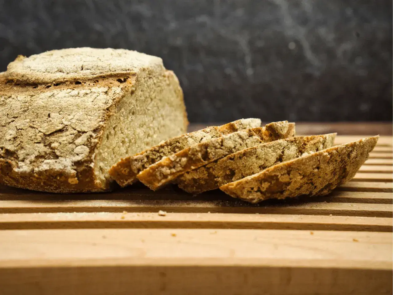 Frisch gebackenes Brot, angeschnitten auf einem Holzbrett. Die Kruste ist rustikal, die Scheiben zeigen die Porosität. Perfekt für die Frage: wie lange brotteig gehen lassen mit trockenhefe.