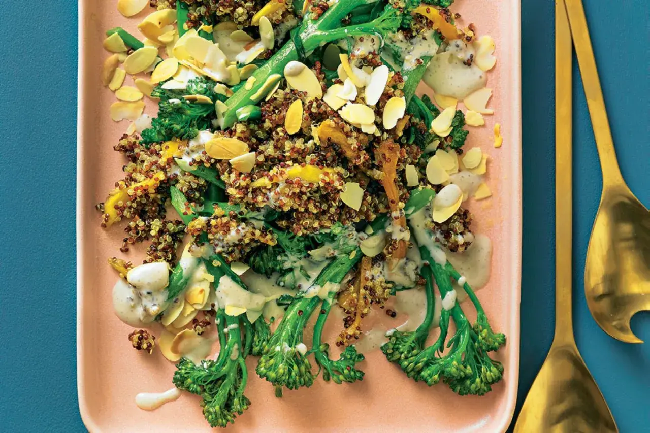 Bunter Quinoa-Salat mit wildem Brokkoli, Mandelsplittern und cremiger Sauce auf einem rosa Teller.