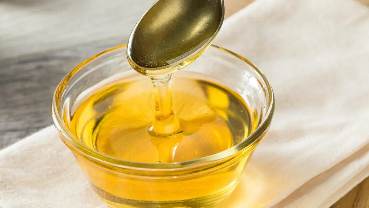 Goldener Sirup fließt von einem Löffel in eine Glasschale. Eine süße Alternative, wenn Sie Agavendicksaft ersetzen möchten.
